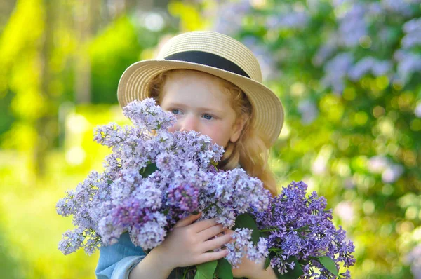 Horizontales Foto eines Mädchens, das Fliederblumen riecht — Stockfoto