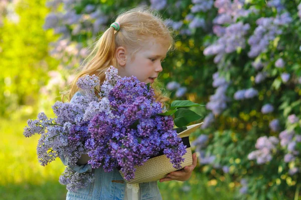 一个带着一束紫丁香的小女孩的水平照片 — 图库照片