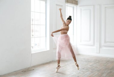 Parlak bir sınıfta dans eden bir balerinin yatay fotoğrafı.