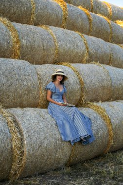 Samanlıkta oturan genç bir kadının dikey portresi