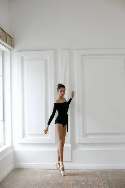 Vertical photo of a young ballerina in a black leotard standing — Stock Photo, Image