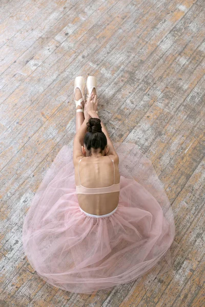Vertical photo of a young ballerina sitting on the floor in the — Stock Photo, Image
