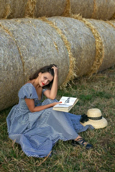 一个阅读女孩在干草堆背景上的垂直肖像 — 图库照片