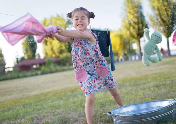一个6岁女孩在洗衣服时扭动衣服的水平照片 — 图库照片