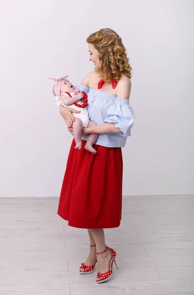 Vertical pin-up photo of a young beautiful woman with a baby in — Stock Photo, Image