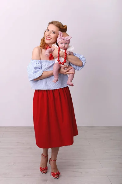 Foto vertical de uma jovem mulher sorridente com um bebê em seus braços — Fotografia de Stock