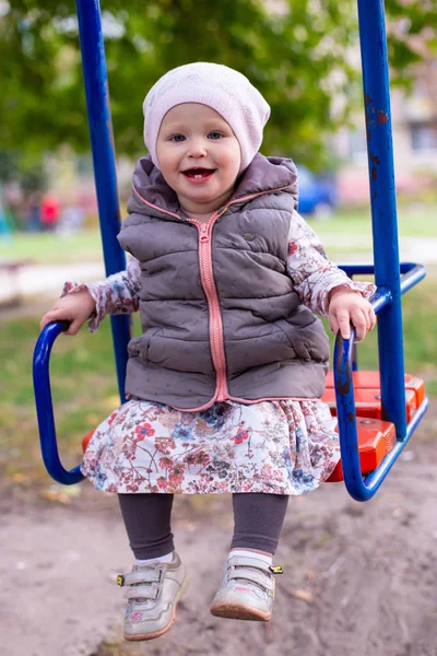 Vertical photo of a little girl riding on a swing — Stock Photo, Image