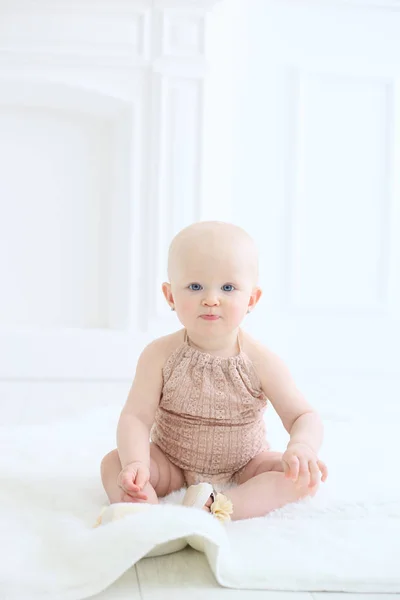 Foto vertical de um bebê sentado no chão em um estúdio branco — Fotografia de Stock