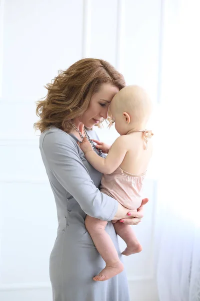 Foto vertical de uma mãe com pequena filha em um quarto brilhante — Fotografia de Stock