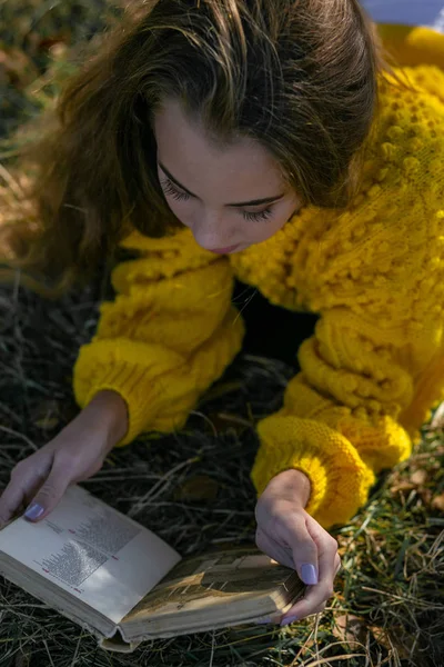 Vertical photo of a young beautiful girl lying with a book in au — 图库照片