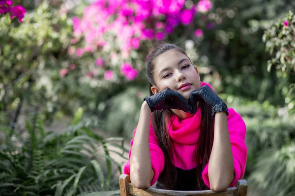 Bella Ragazza Seduta Una Sedia Uno Sfondo Verde Lussureggiante — Foto Stock