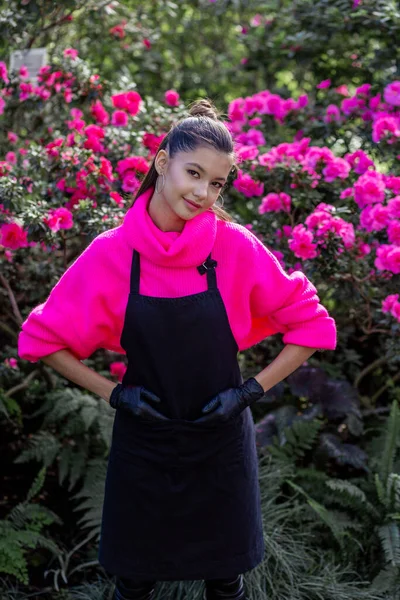 Νεαρό Κορίτσι Κηπουρός Στέκεται Ένα Φόντο Από Όμορφα Φυτά — Φωτογραφία Αρχείου