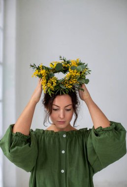 Koyu saçlı genç Avrupalı kafasına mimoza çelengi takıyor.