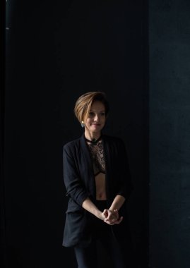 Güzel kısa saçlı kadın duruyor ve gizemli bir şekilde gülümsüyor.