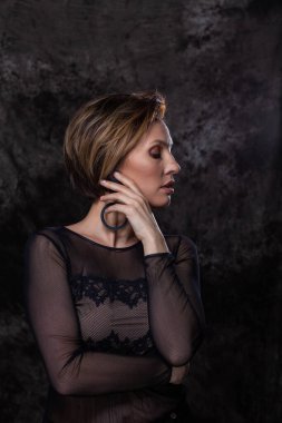 Güzel bir kadın profilde durup yüzüne hafifçe dokunuyor.