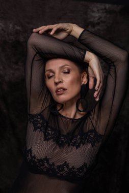 Genç kadın gözlerini kapatıyor ve kollarını başının üstüne kaldırıyor.