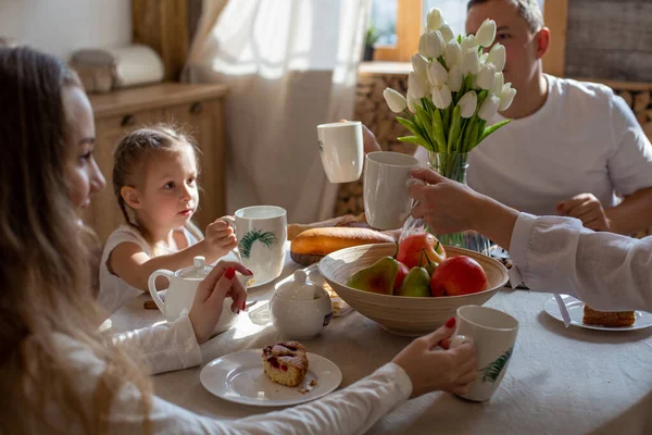 friendly family: mom, dad and two daughters have breakfast together in the family kitchen