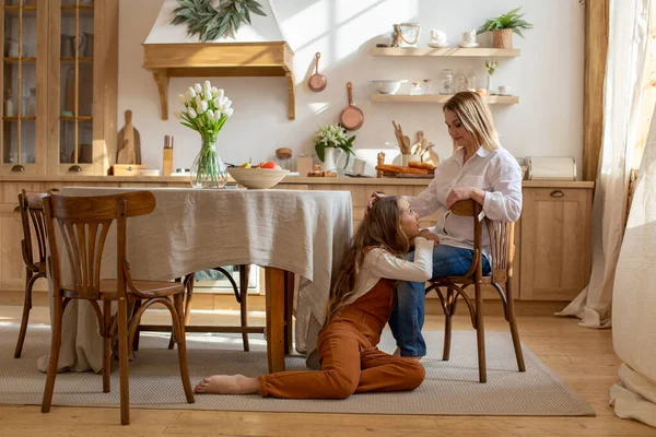 mom and daughter enjoy talking to each other in the family kitchen