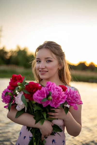Uśmiechnięta Dziewczyna Bukietem Czerwonych Różowych Piwonii Stoi Tle Pięknej Przyrody — Zdjęcie stockowe
