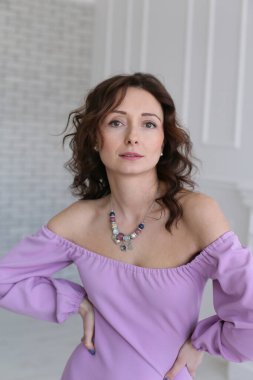 tutkulu koyu saçlı genç Avrupalı kadın parlak bir odada dikiliyor ve doğrudan kameraya bakıyor.