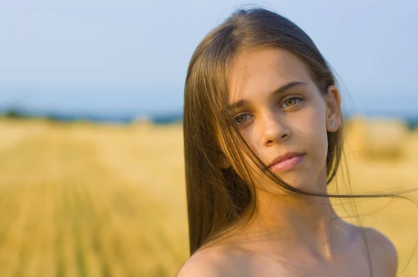 一个多愁善感的少女 留着长长的头发 一双忧伤的绿眼睛 站在一块割过的麦田上 — 图库照片