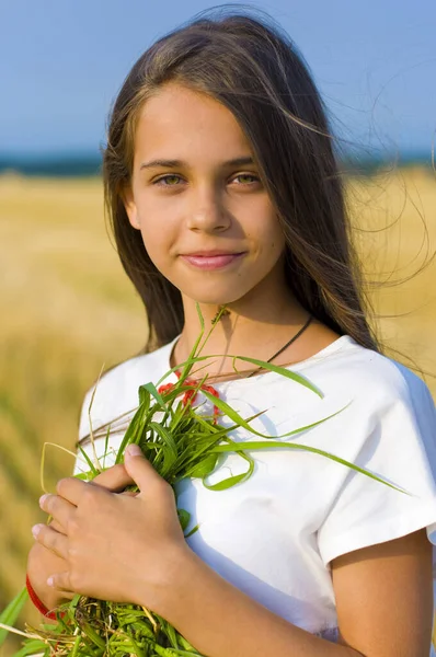 少女站在割下的麦田上 手里拿着一个长满青草的花环 笑得很可爱 — 图库照片