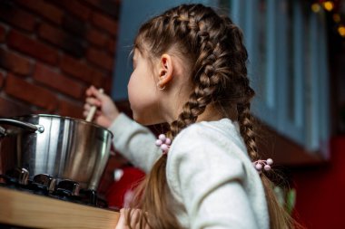Küçük kız evde mutfakta çorba yapmayı öğreniyor.