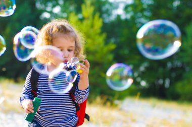 Güzel kıvırcık bebek baloncuklar çıkarmaya çalışıyor.