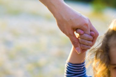 Kıvırcık bebek annesinin elini tutuyor.