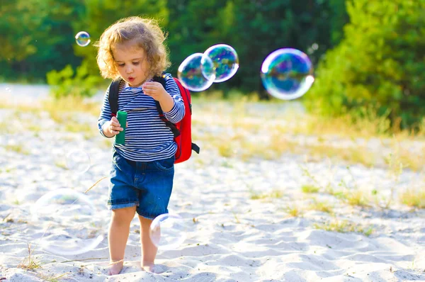 Забавный Кудрявый Ребенок Учится Дуть Мыльные Пузыри Пляже Фоне Ярко — стоковое фото
