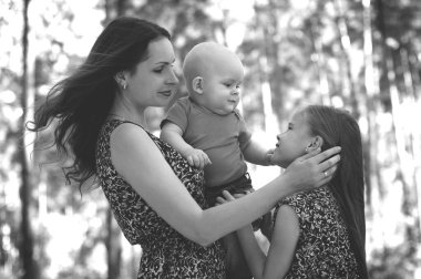 happy family stands in the middle of the forest and mother gently looks at her beloved daughter clipart