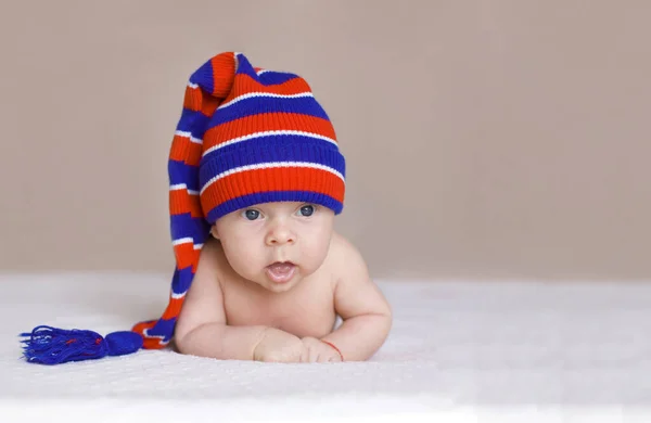 Baby Striped Knitted Hat Pompom Lies White Blanket Looks Carefully — Stock Photo, Image