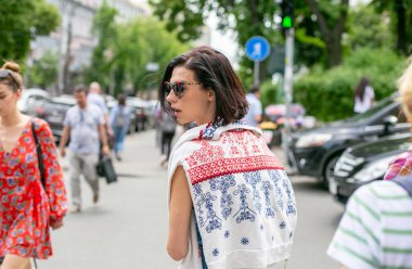 Güneş gözlüklü güzel kız şehir caddesinde başıboş dolaşıyor.