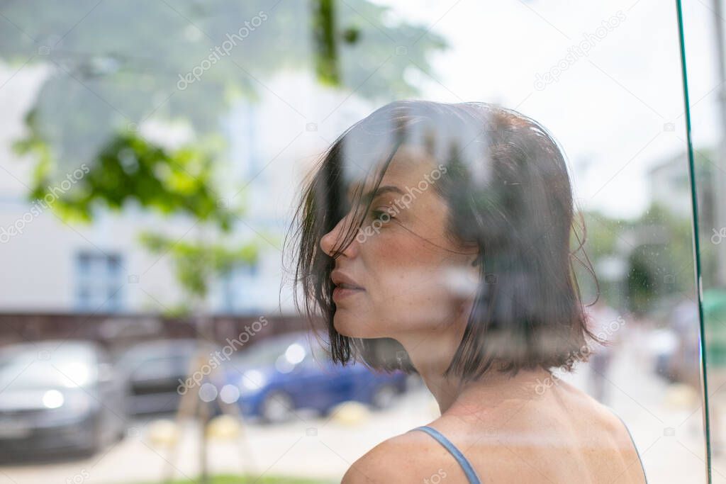 lovely young brunette with short hair stands thoughtfully at the shop window