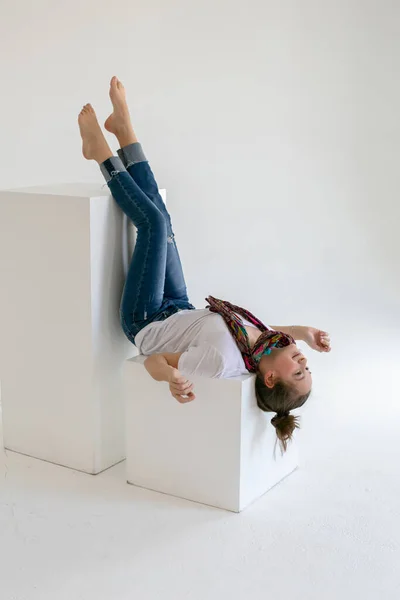 Blootsvoets Tiener Meisje Blauwe Jeans Ligt Ondersteboven Een Witte Kubus — Stockfoto