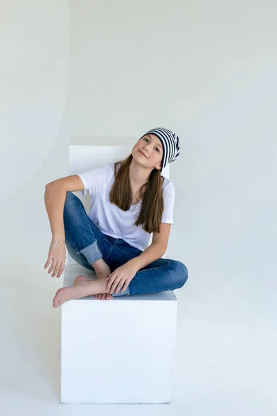 Lovely Teenager Girl Blue Jeans White Shirt Striped Hat Sits — Stock Photo, Image
