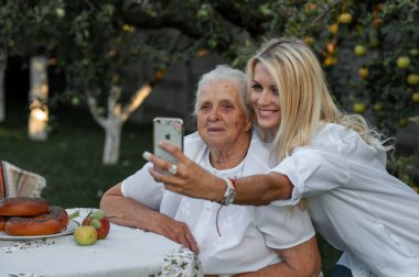 Güzel sarışın, sevgili büyükannesiyle bahçede fotoğraf çekiyor.
