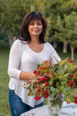 50 yaşındaki esmer kadın bahçedeki masayı hazırlıyor.