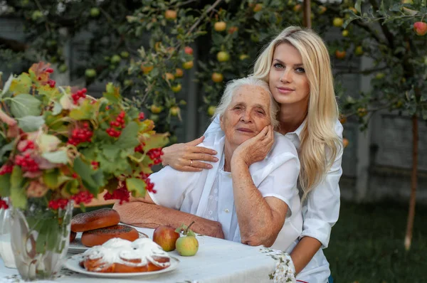 Schöne Blonde Umarmungen Von Hinter Ihrer Geliebten Großmutter Vor Der Stockfoto