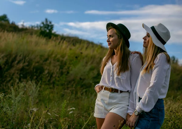 Two Cheerful Adult Sisters Hats White Blouses Shorts Standing Grassy — Stock Photo, Image