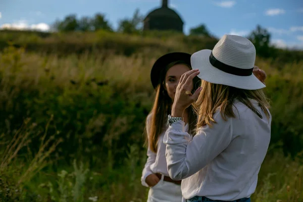 Two Cute Adult Sisters Hats White Blouses Shorts Standing Grassy — Stock Photo, Image