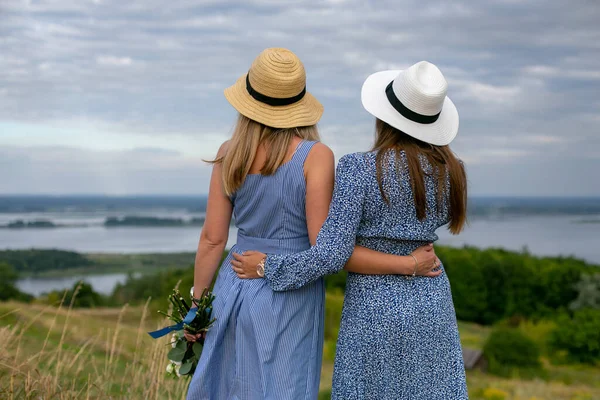 Две Молодые Длинноволосые Женщины Голубых Летних Платьях Шляпах Стоят Спиной — стоковое фото