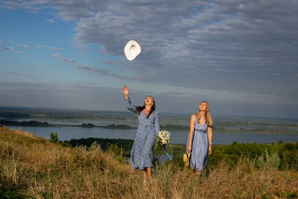 Дві Щасливі Молоді Дівчата Блакитних Літніх Сукнях Ходять Уздовж Трав — стокове фото