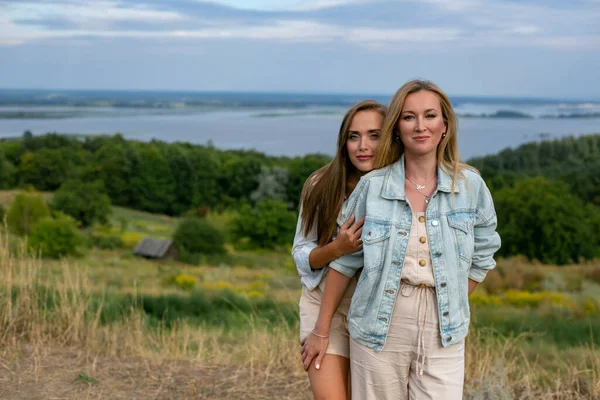 两个可爱的成年女友站在令人叹为观止的夏日乡村风景的背景下 — 图库照片