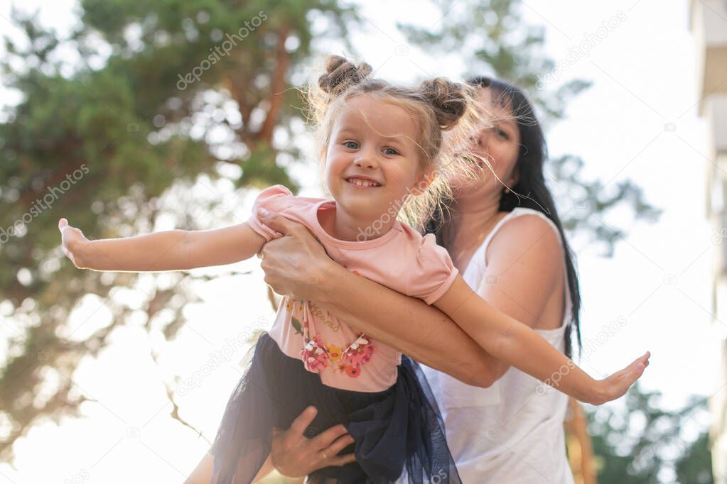 funny little girl enjoys a game with her mom for a walk in the summer park