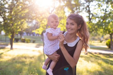 Bir yaşındaki bebek ve genç annesi gün batımında yaz parkında birlikte vakit geçirmeyi severler.
