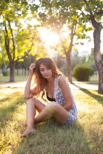 日落时分 赤脚的欧裔人坐在夏日公园的草地上 — 图库照片