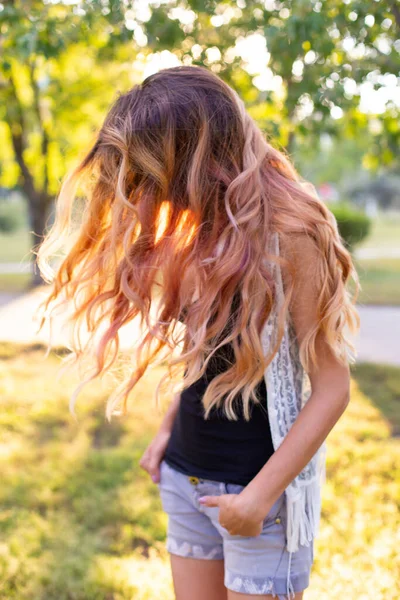 穿着牛仔裤短裤的瘦小女孩站在一个夏天的公园里 美丽的长发在风中飘扬 — 图库照片