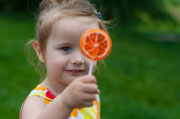 穿着鲜艳夏装的可爱小宝宝很高兴看到她面前的棒子上有糖果 — 图库照片