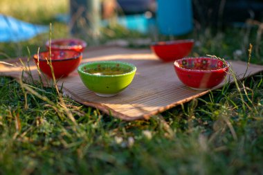 Bambu hasırının üzerinde yeşil çay standı olan çok renkli kaseler.